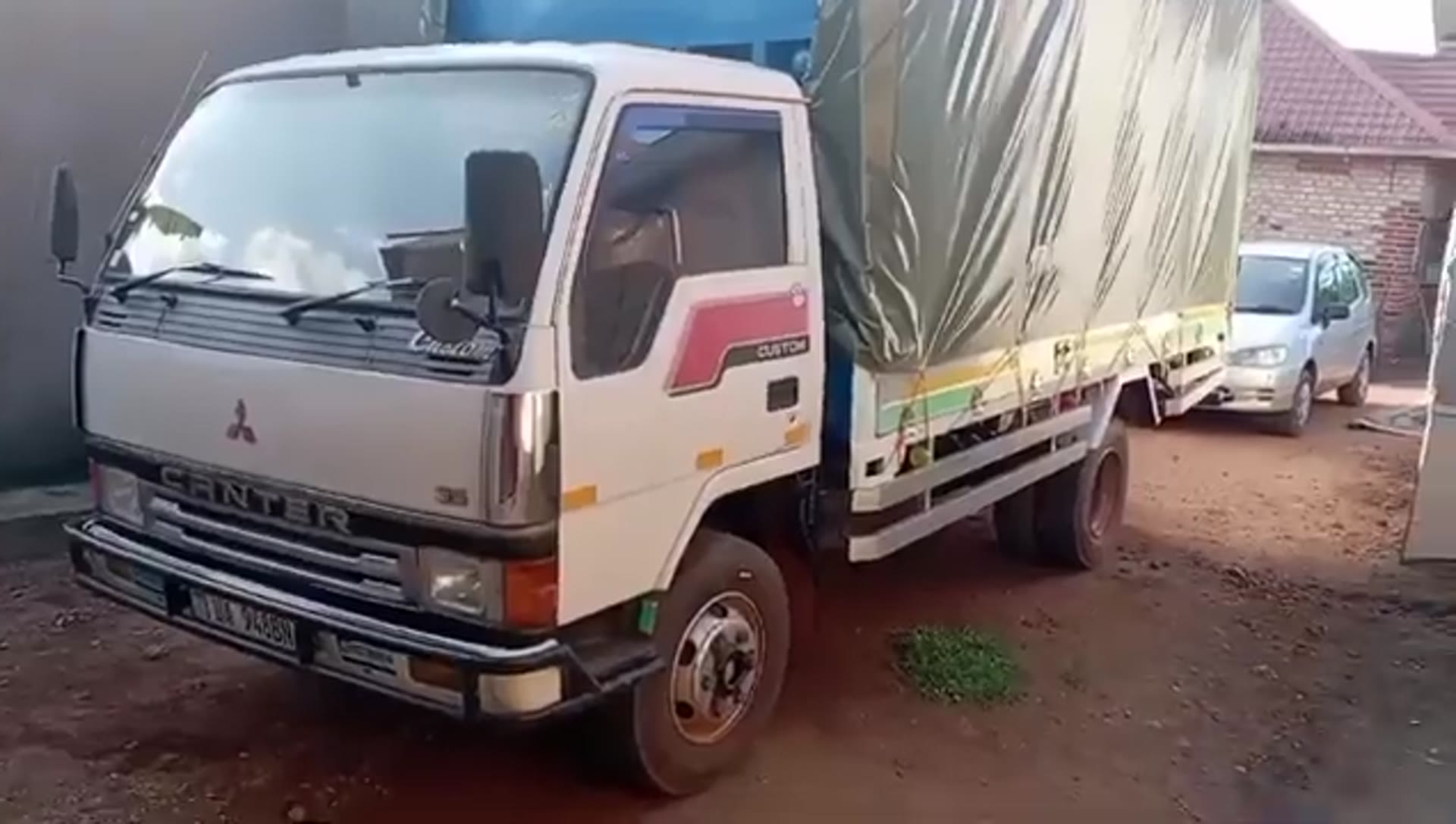 The Fortune Farms Mitsubishi Canter delivery truck, loaded under a canvas canopy, parked on the farm.